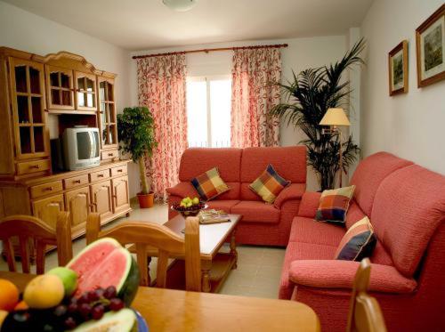 a living room with a red couch and a table at Apartamentos Miguel Angel in Estepona