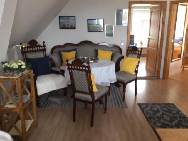 uma sala de jantar com uma mesa e cadeiras com almofadas amarelas em Theodor Storm Unterkünfte 2 em Husum