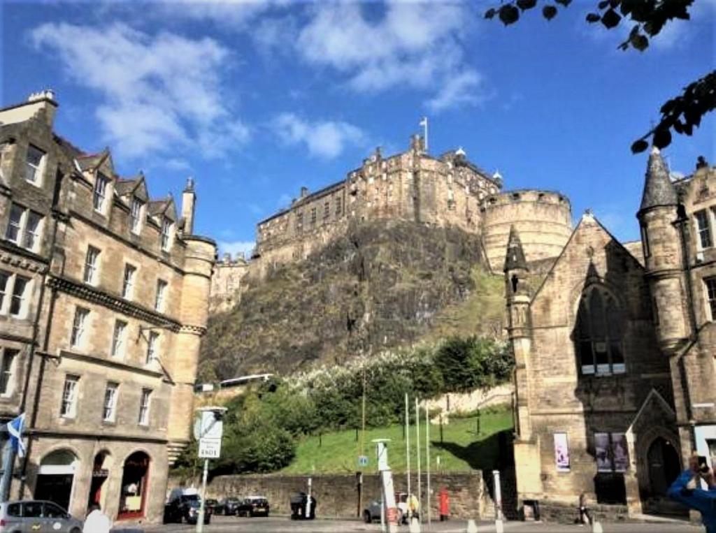 ein Schloss auf einem Hügel neben Gebäuden in der Unterkunft Kick Ass Grassmarket (18+) in Edinburgh