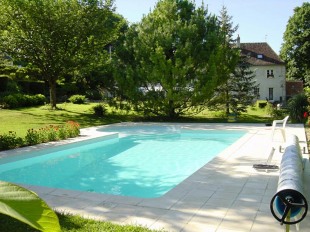 a swimming pool in the yard of a house at Le Moulin Garnier in Vernou-sur-Brenne