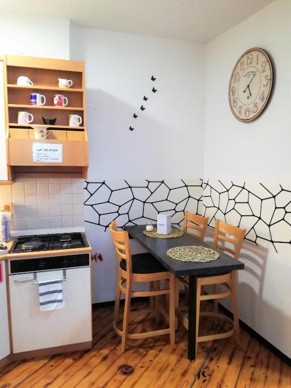 a kitchen with a table and chairs and a clock on the wall at pavliha in Ljubljana