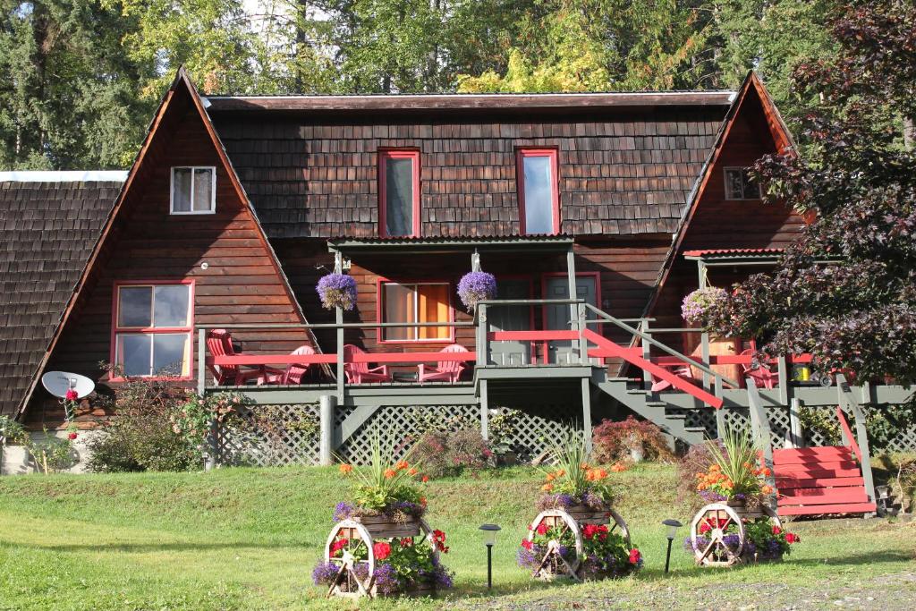 a log cabin with a porch and red chairs in the yard at Sunny Bluffs Chalets in Kaslo