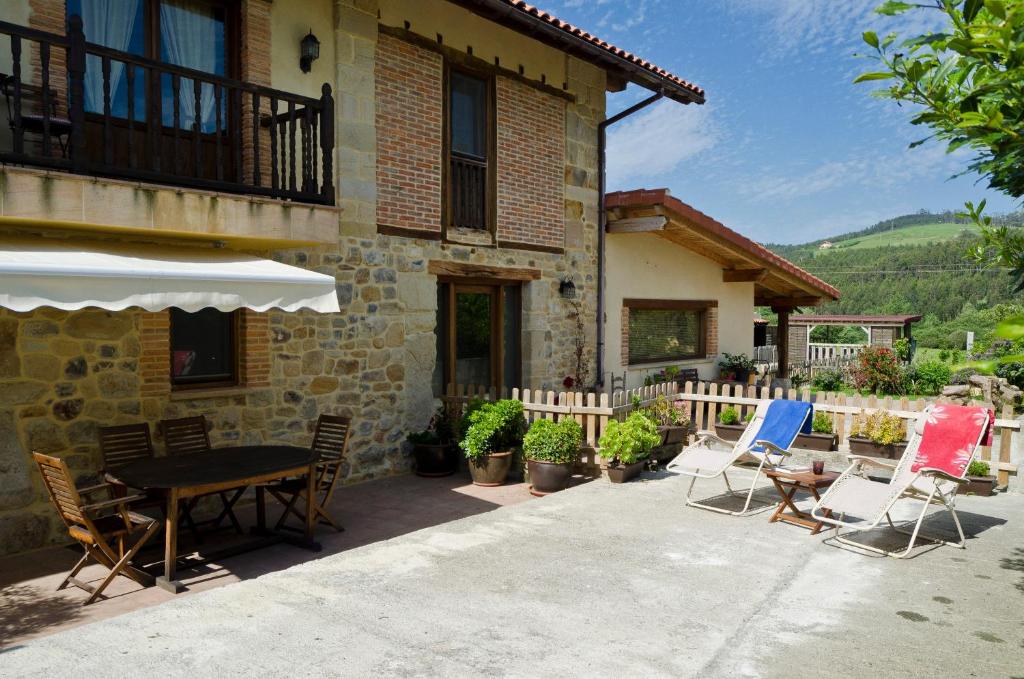 a patio with chairs and a table in front of a house at Apartamentos Playa Galizano in Galizano
