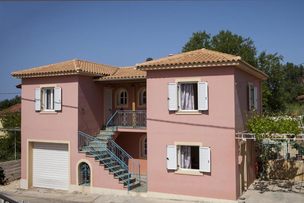 una casa rosa con escaleras delante en Kantouni Apartments, en Svoronata