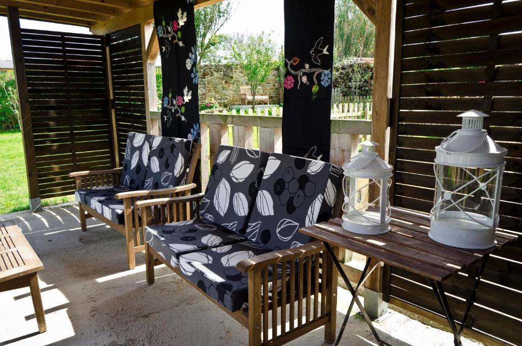 a porch with two chairs and a table with a lantern at Apartamentos Playa Galizano in Galizano