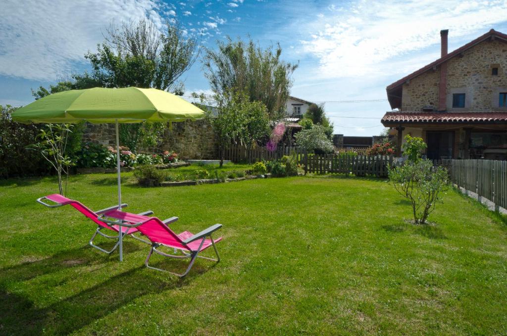 two chairs and an umbrella in a yard at Apartamentos Playa Galizano in Galizano