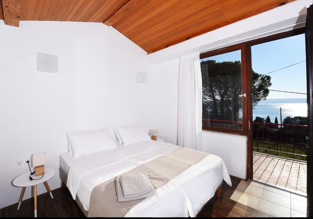 a white bedroom with a bed and a large window at Modern & Comfy Sea View House NG in Portorož
