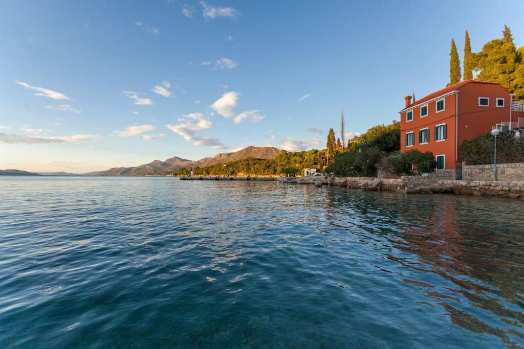 un bacino d’acqua con un edificio rosso sullo sfondo di Apartment Esperanza a Koločep