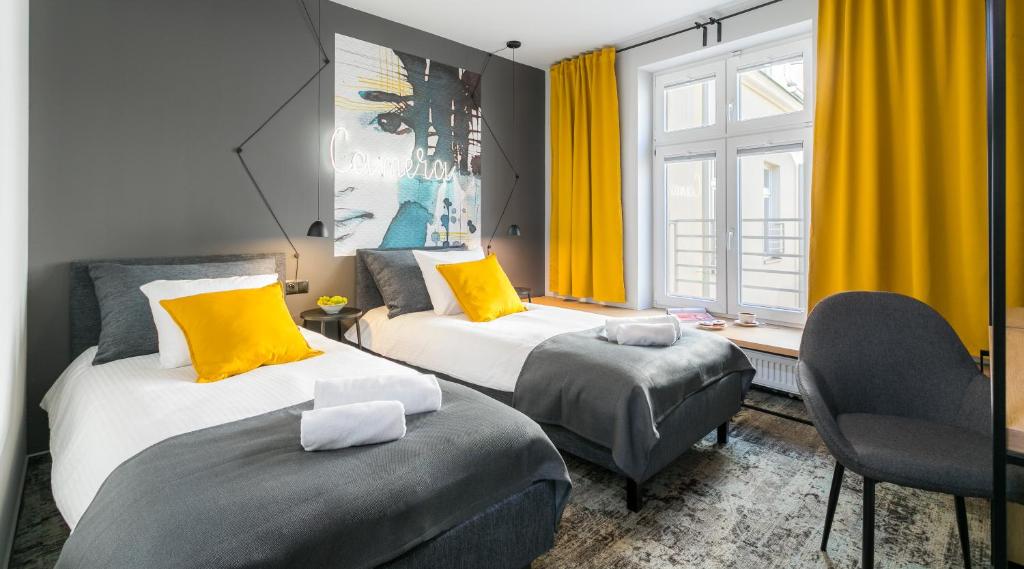 duas camas num quarto com cortinas amarelas em Camera Apartments em Cracóvia