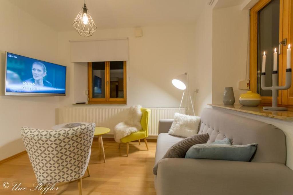 Una sala de estar con un sofá y sillas y un televisor. en Ferienwohnung Maierers Schaiere, en Gammesfeld