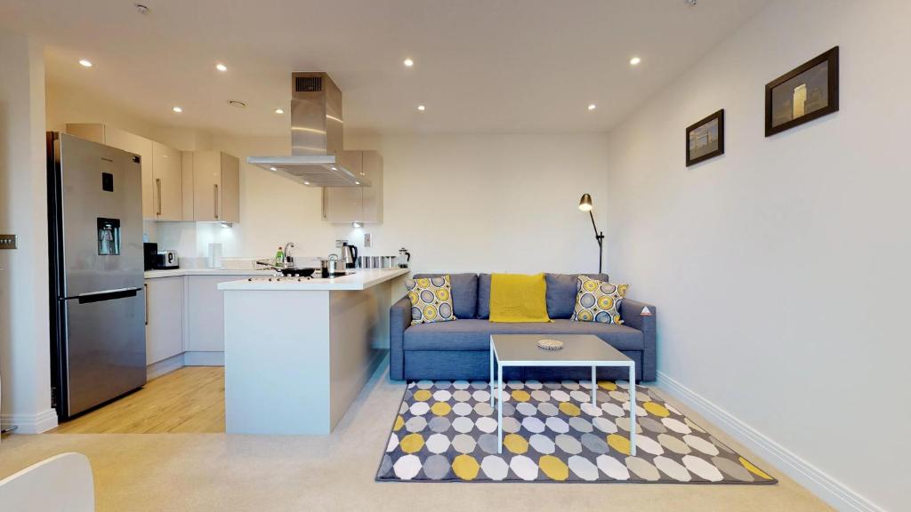 a living room with a blue couch and a kitchen at NIKSA Serviced Accommodation - Welwyn Garden City Business Park in Welwyn Garden City