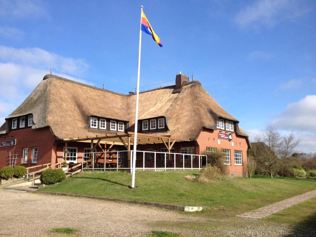 um grande edifício com uma bandeira em frente em Inselhotel Kapitän Tadsen / Amrum em Nebel