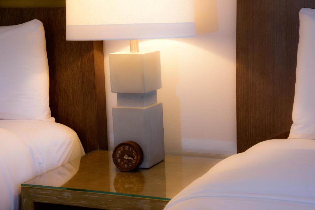 a table with a clock on it next to two beds at Sunset Inn in Islamorada