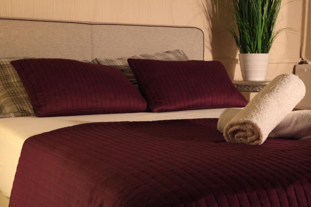 a bed with two burgundy cushioned pillows at Sleep Well Rooms in Stuttgart