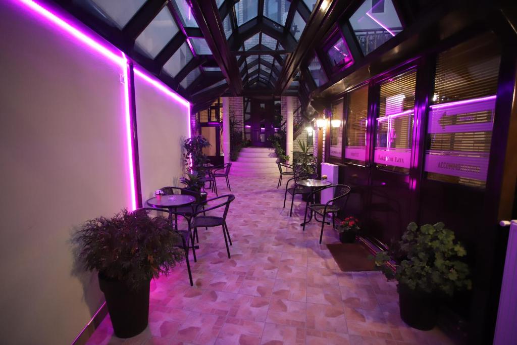 Zimmer mit Tischen, Stühlen und violetten Lichtern in der Unterkunft Garni Hotel Laguna Lux in Niš