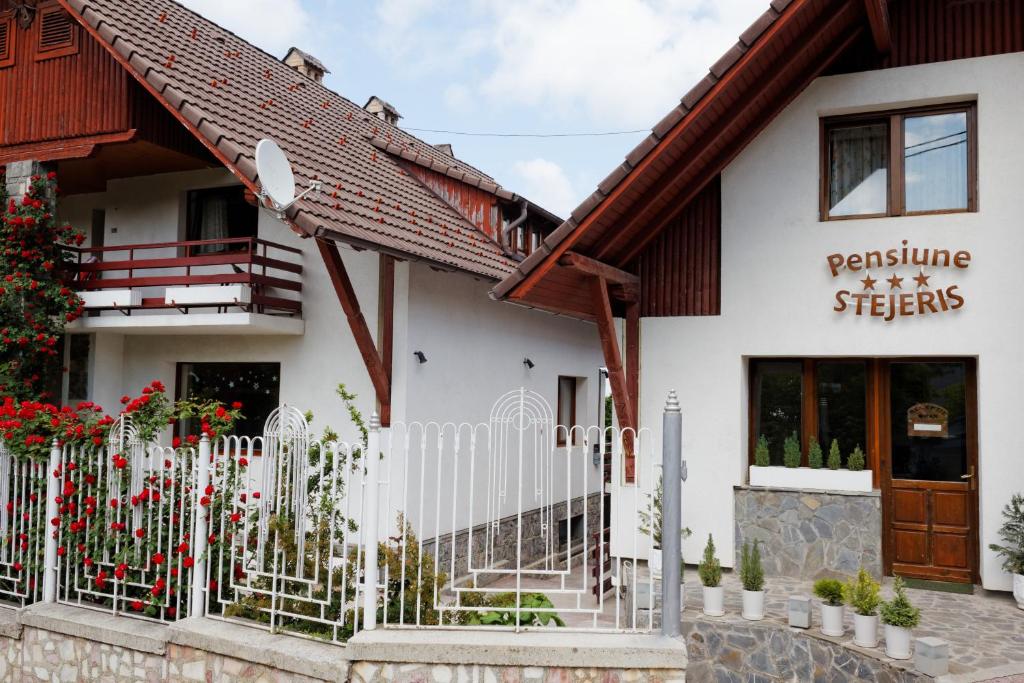 a white building with a fence in front of it at Pension Stejeris in Braşov