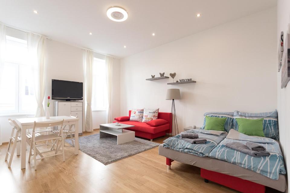 salon z łóżkiem i czerwoną kanapą w obiekcie Bright Red Heart Apartment in Leopoldstadt w Wiedniu