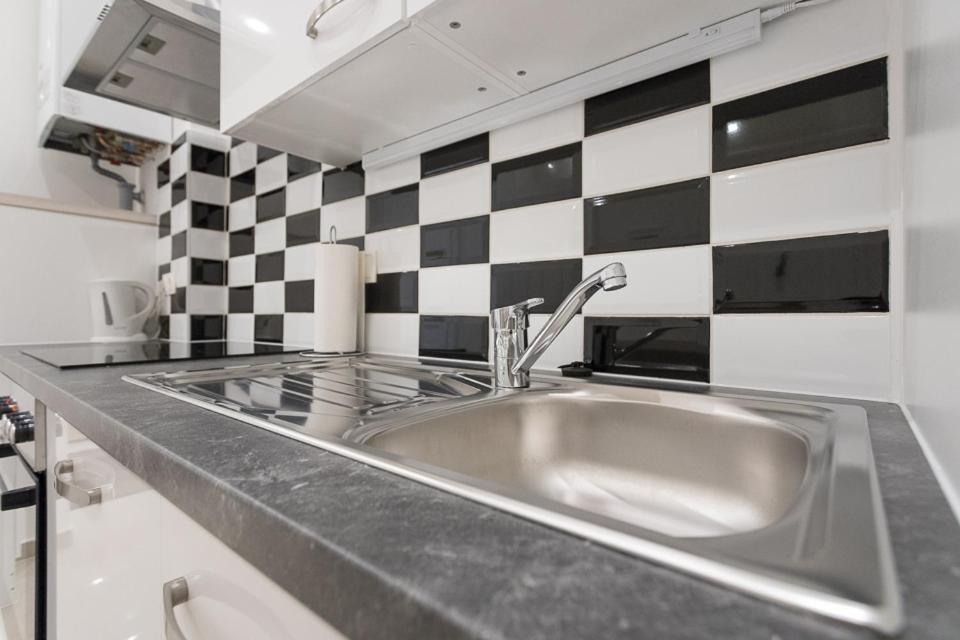 zlew w kuchni z czarno-białą ścianą wyłożoną kafelkami w obiekcie Bright Red Heart Apartment in Leopoldstadt w Wiedniu