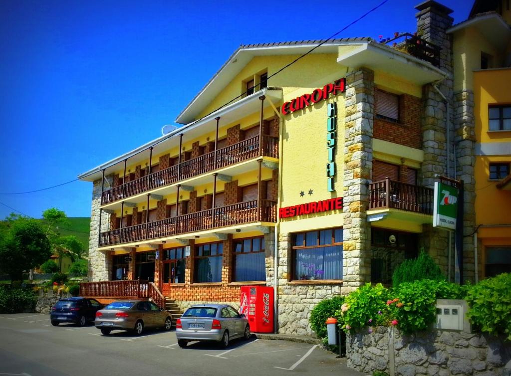 un bâtiment avec des voitures garées devant lui dans l'établissement Hostal Europa, à San Roque del Acebal