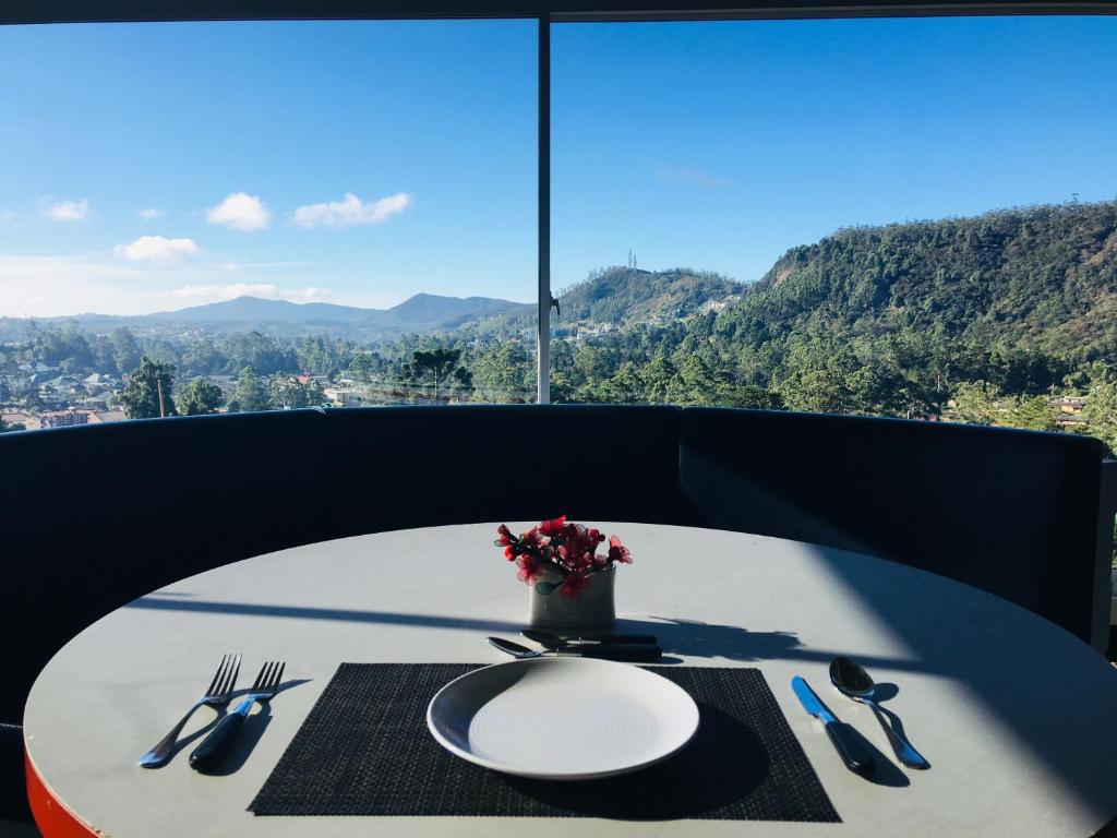 una mesa con un plato y un jarrón con flores. en Namadi Nest, en Nuwara Eliya