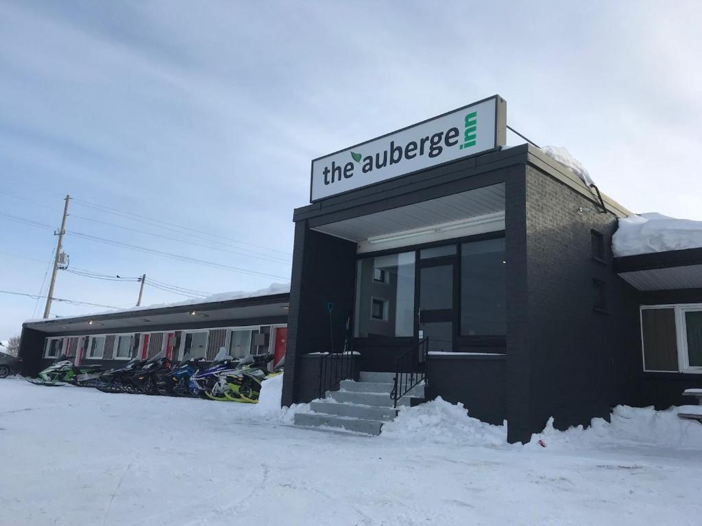 un edificio con un cartel en la nieve en The Auberge Inn, en New Liskeard