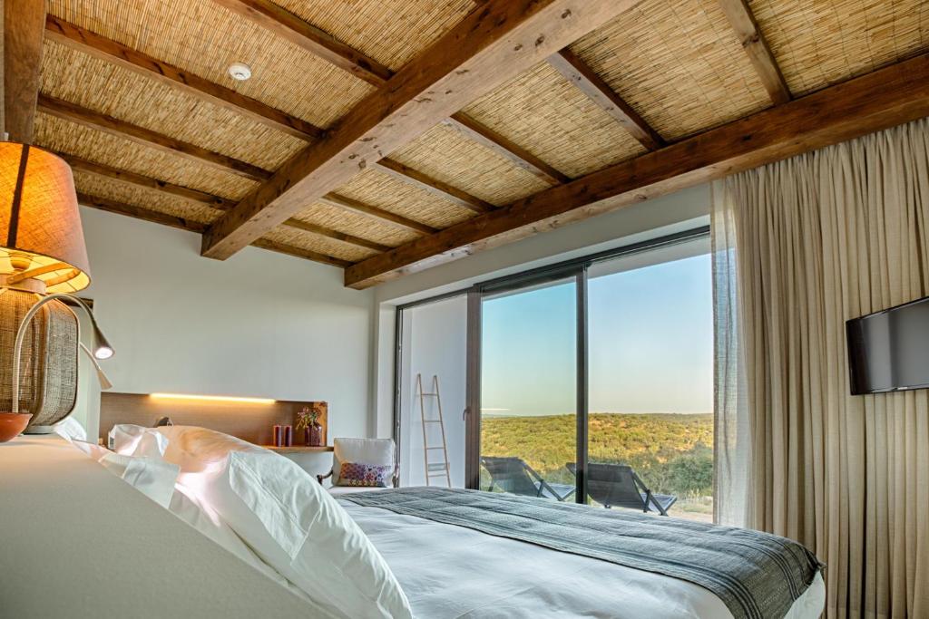 a bedroom with a bed and a large window at Monte Velho Equo-Resort in Arraiolos