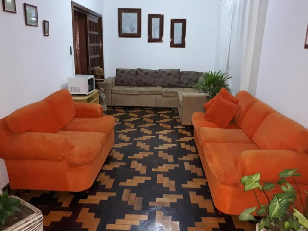 a living room with two orange couches and a couch at Central 1 in Uruguaiana