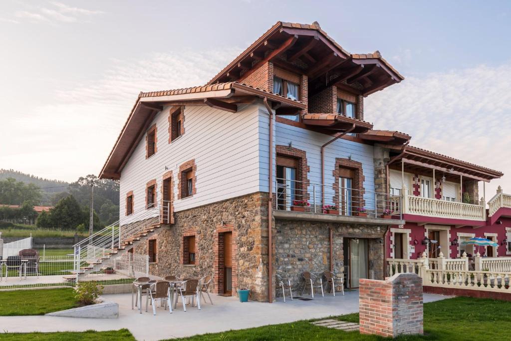 Casa grande con balcón y mesas. en Apartamentos Turísticos el Pontón, en Arnuero