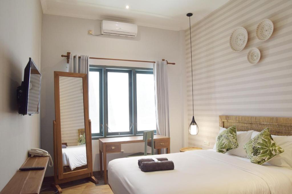 a bedroom with a large white bed and a mirror at Grhatama Guest House in Yogyakarta