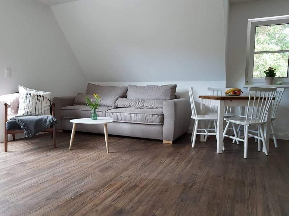 a living room with a couch and a table and chairs at Darßer Strandgut - Haus Ahrenshooper Holz in Ahrenshoop