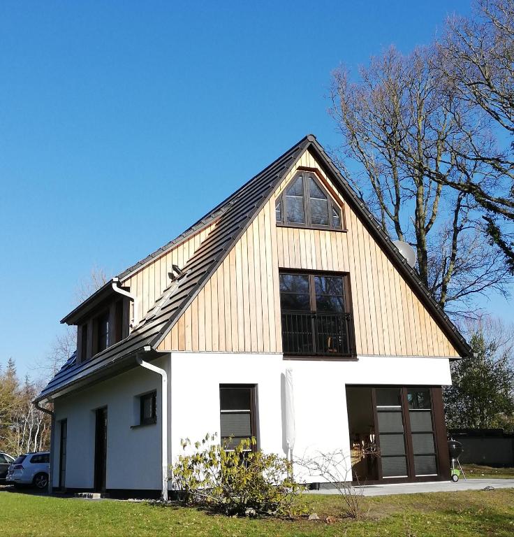 a white house with a gambrel roof at Darßer Strandgut - Haus Ahrenshooper Holz in Ahrenshoop