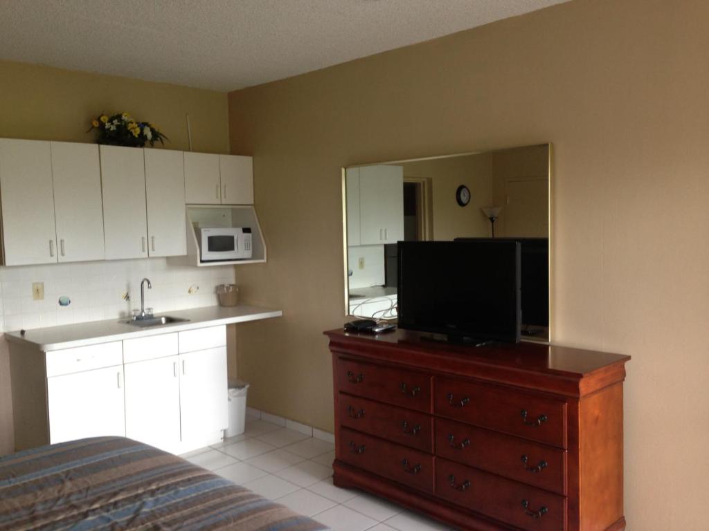 a room with a kitchen and a dresser with a television at Knights Inn Hallandale in Hollywood