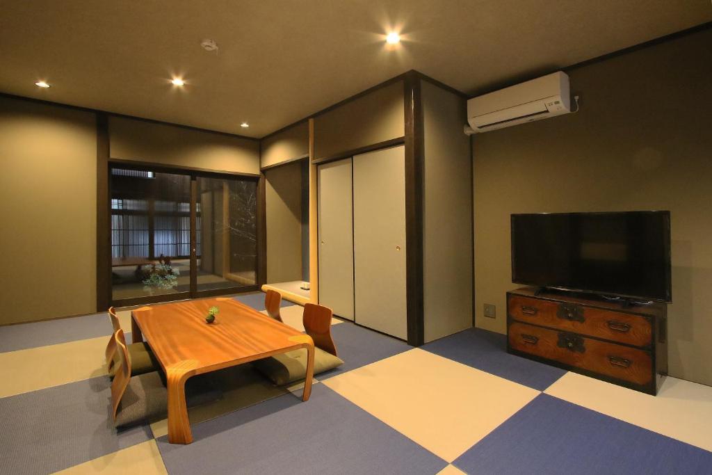 ein Wohnzimmer mit einem Holztisch und einem TV in der Unterkunft Chizuruan in Kyoto