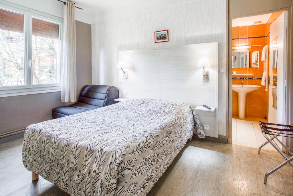 um quarto de hotel com uma cama e uma cadeira em Le Provençal em Tarascon