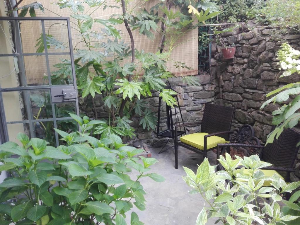 un jardín con una pared de piedra, una silla y plantas en Le Ortensie, en Dolcedo