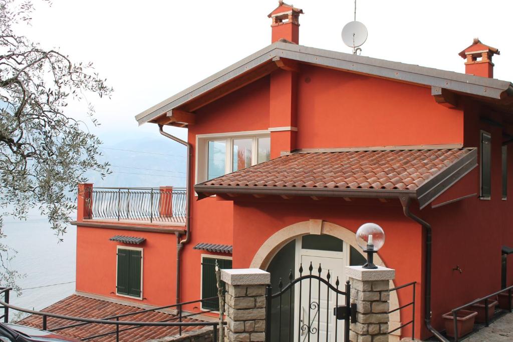 a red house with a gate and a balcony at B&B Lil in Brenzone sul Garda