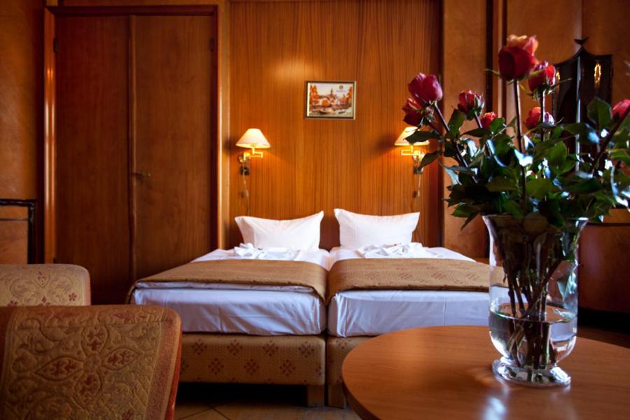 una camera d'albergo con due letti e un tavolo con fiori di Hotel Aster an der Messe a Berlino