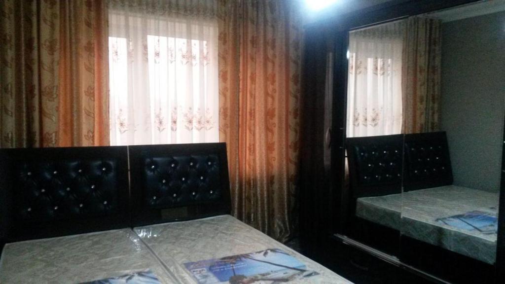 a bedroom with two beds and a window with curtains at Квартира 2-ух комнатная в центре города in Fergana