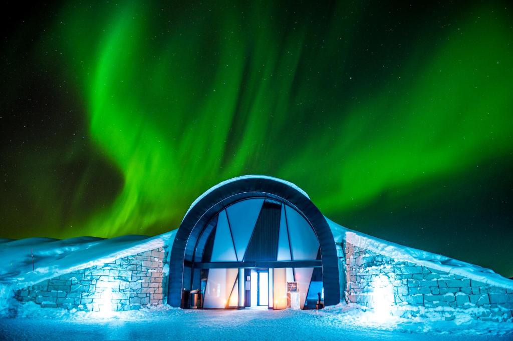 an igloo in the snow under the northern lights at Icehotel in Jukkasjärvi