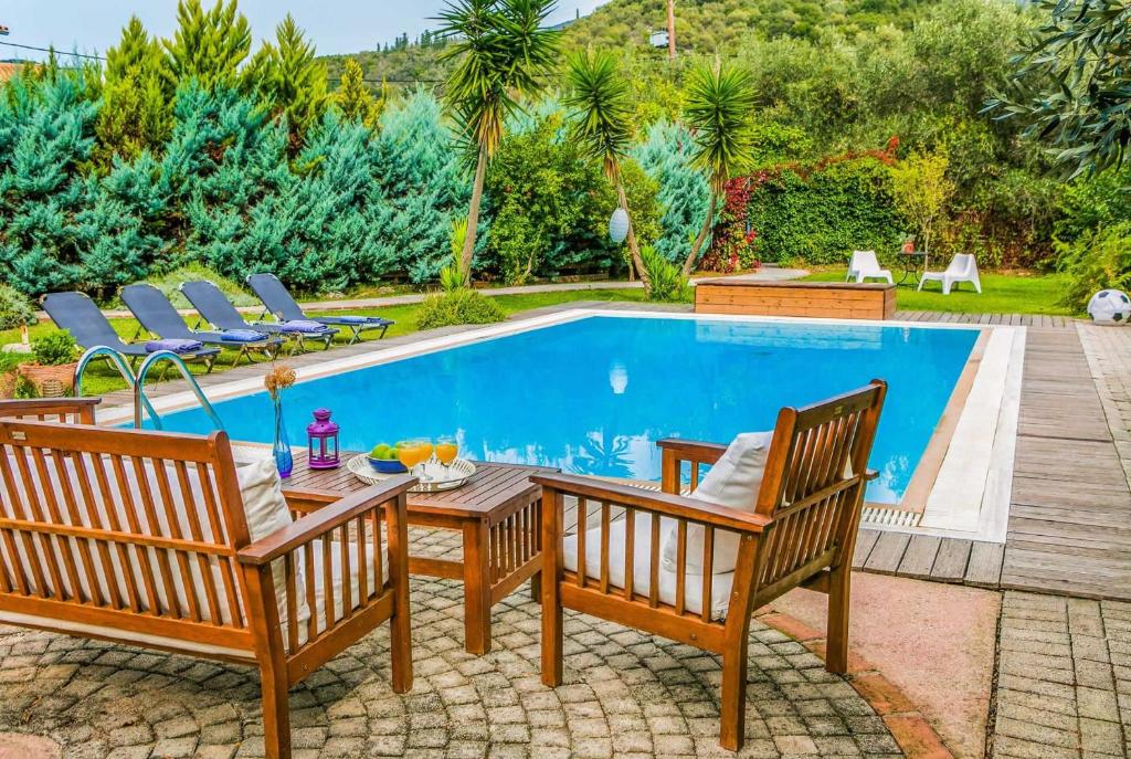 a swimming pool with two chairs and a table next to it at Gialos I in Mikros Gialos