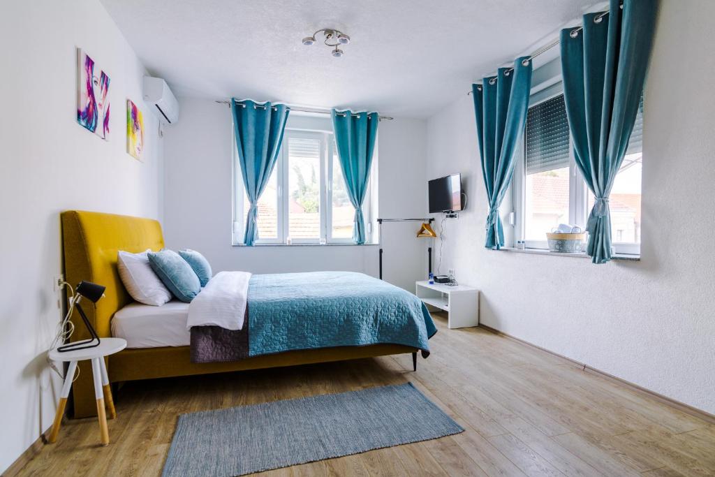 - une chambre avec des rideaux bleus et un lit avec une couverture bleue dans l'établissement Apartmani Moon, à Trebinje