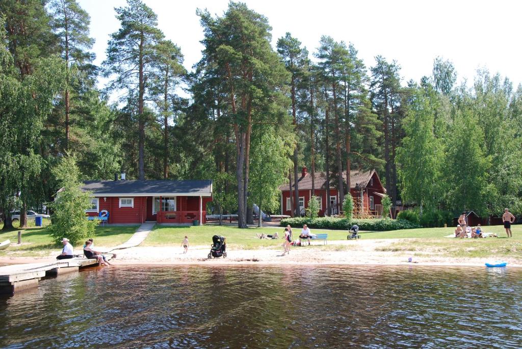 a group of people on a beach near a lake at Camping Toivolansaari in Ikaalinen