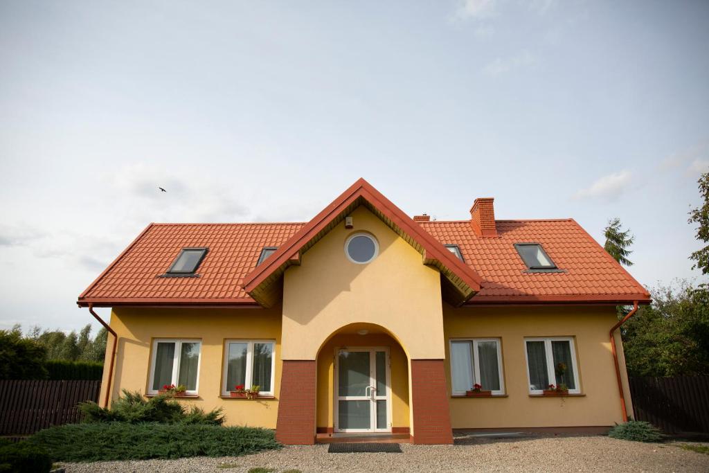 une maison jaune avec un toit rouge dans l'établissement Agroturystyka Słoneczny Dom, à Lublin