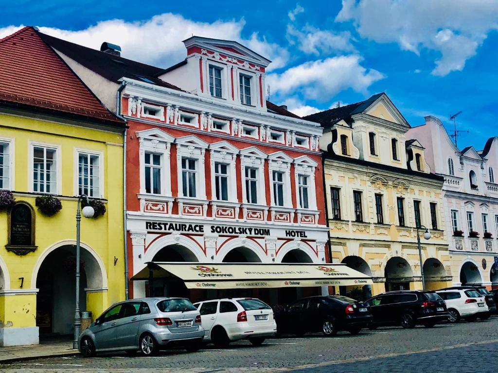 eine Gruppe von Gebäuden auf einer Straße mit parkenden Autos in der Unterkunft Hotel Sokolský Dům in Domažlice