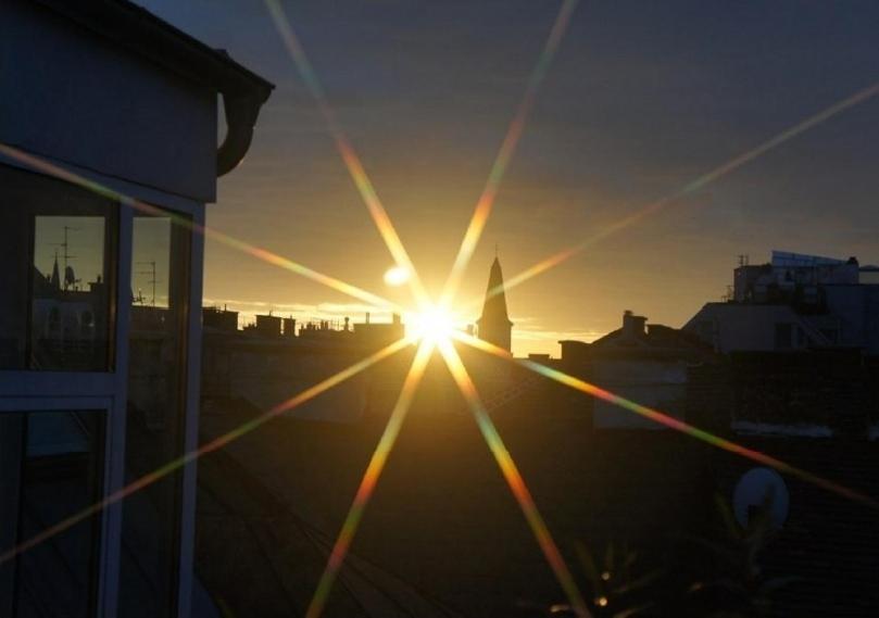 a sun setting in the sky over a city at Rennweg Top Apartment in Vienna