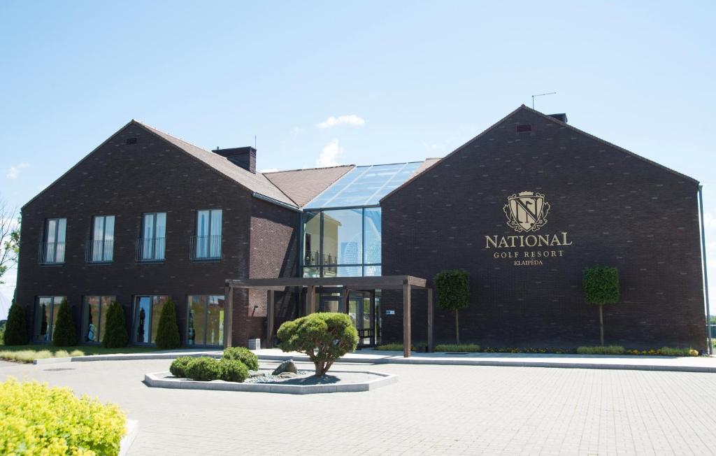 a black building with a tree in front of it at National Golf Resort in Klaipėda