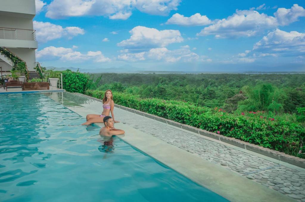 un hombre y una mujer sentados en una piscina en un resort en Panja Resort Palawan, en Puerto Princesa City