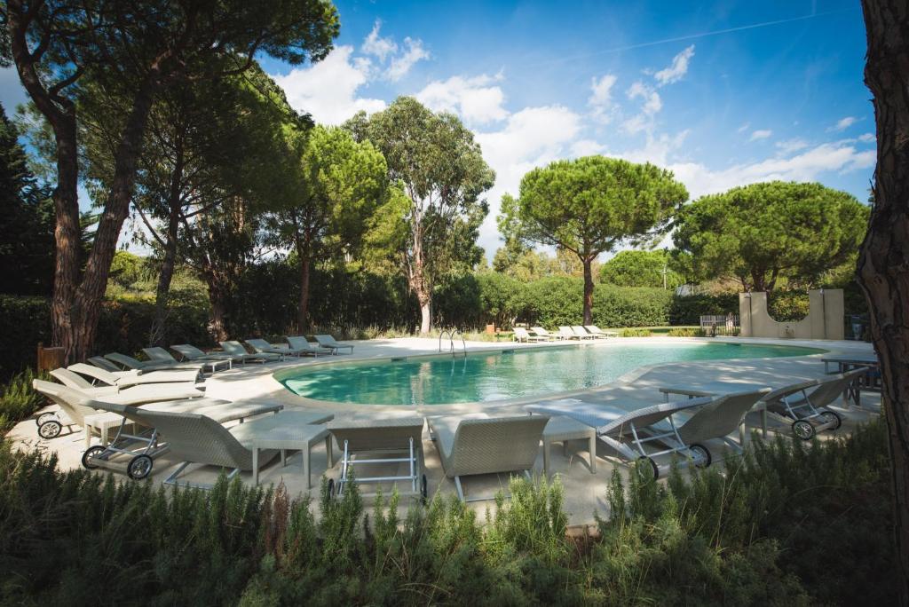 a swimming pool with chairs and a fountain at Roccamare Resort - Casa di Levante in Castiglione della Pescaia