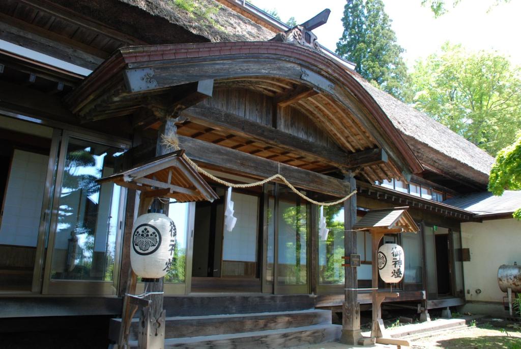 a building with a wooden roof with a porch at Oshi Ryokan in Nagano