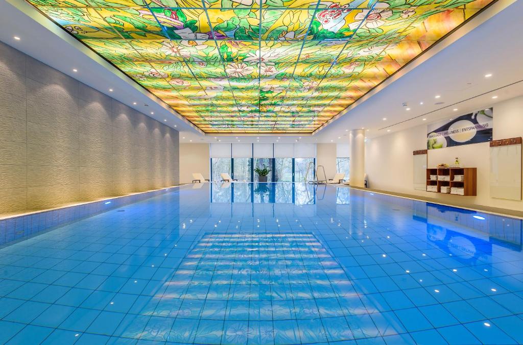 a swimming pool with a colourful ceiling and a swimming pool at Maritim Hotel Bremen in Bremen